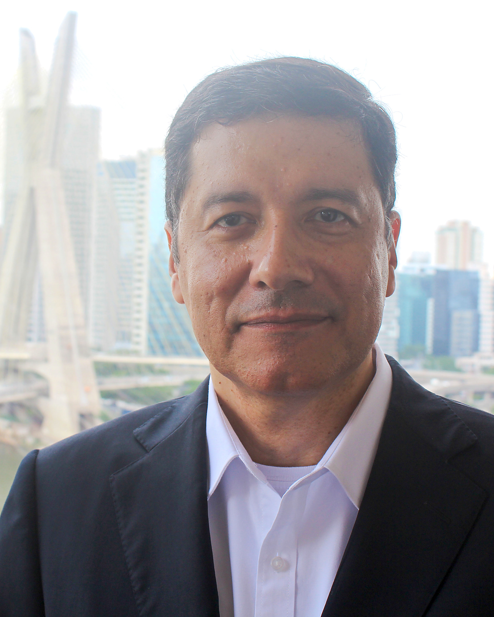 Retrato de Silvio Celestino em duotone marinho, com a Ponte Estaiada e o skyline de São Paulo ao fundo